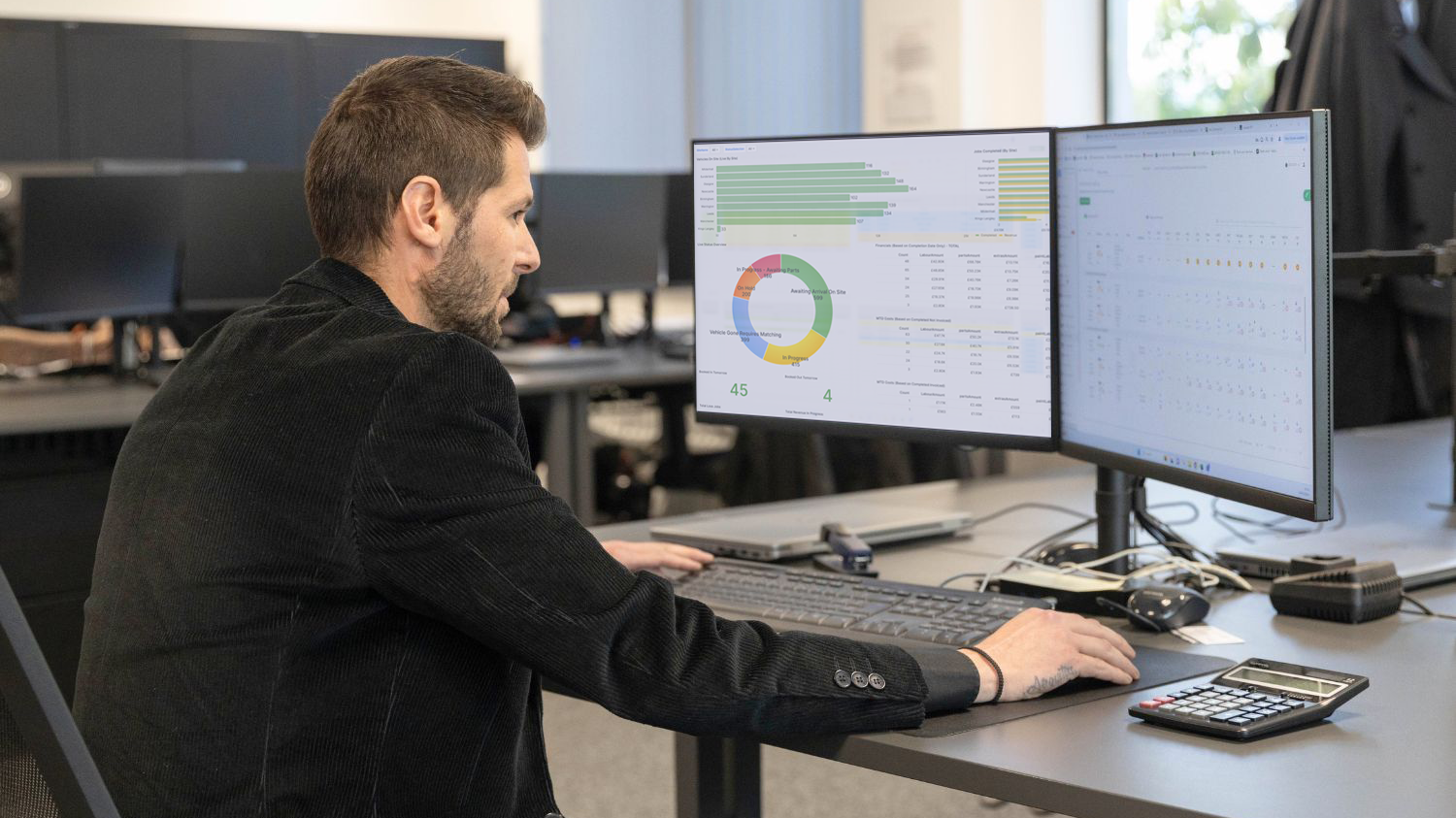 A bodyshop manager sitting in the office of a repair network bodyshop, tracking live business performance data and employee productivity insights through the intuitive bodyshop management system, Onyx BMS.